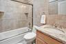 4th Bedroom - ensuite full bathroom with vanity, tile walls, shower / bath combination with glass door, and backsplash