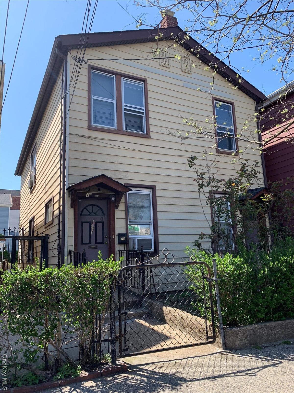 View of front of home featuring a gate, a chimney, and cooling unit