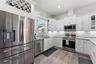 Open-concept kitchen with solid-wood cabinetry, granite countertops, stainless steel appliances, and custom lighting including under-counter kitchen l