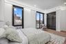 Bedroom featuring wood finished floors, radiator, a city view, recessed lighting, and baseboards