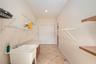 “Spacious indoor laundry room featuring a utility sink, lower cabinetry for organized storage, and additional wired shelving