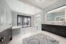 It features dual expansive vanities, square sinks, custom tile backsplash, backlit mirrors with integrated TV feature.