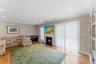 Hardwood flooring throughout featuring a fireplace with a white mantel and dark hearth, built-in recessed lighting, crown molding, and a sliding glass