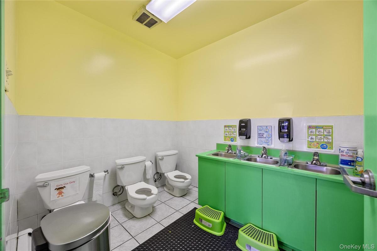 Bathroom featuring tile patterned flooring, a wainscoted wall, and tile walls