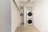 Washroom featuring stacked washer and clothes dryer and tankless water heater