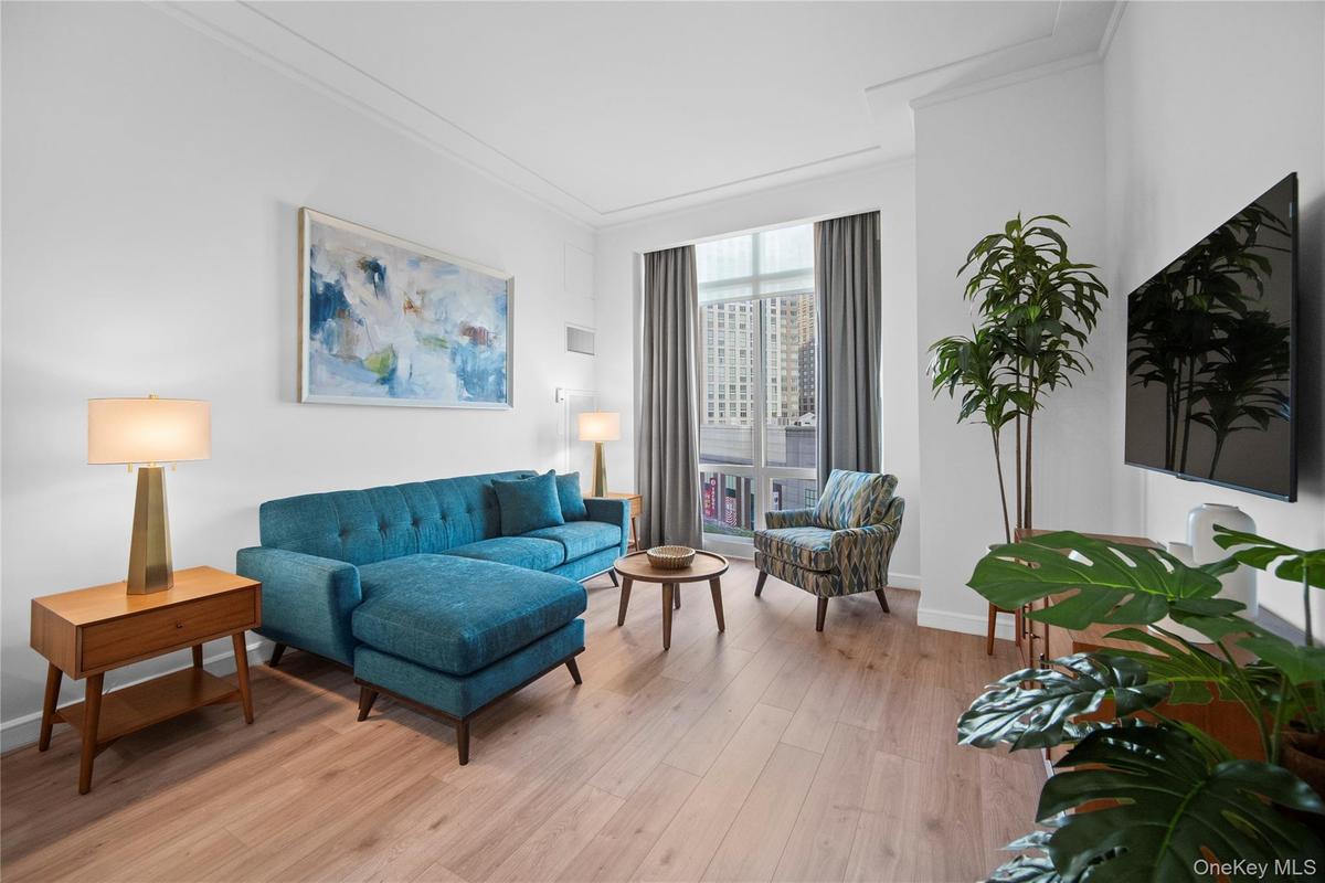 Living area with light wood-style flooring, crown molding, and baseboards