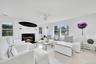 Living area featuring healthy amount of natural light, a baseboard radiator, wood finished floors, and a glass covered fireplace
