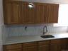 Kitchen featuring a sink, tasteful backsplash, brown cabinets, and light stone countertops