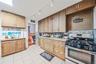 Kitchen featuring stainless steel appliances, rail lighting, light tile patterned flooring, decorative backsplash, and light stone countertops