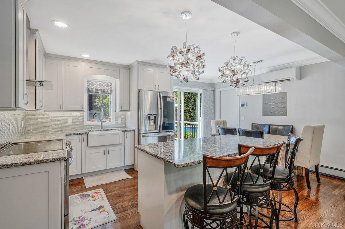 Kitchen featuring appliances with stainless steel finishes, a breakfast bar area, dark wood-type flooring, tasteful backsplash, and pendant lighting