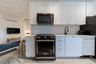 Kitchen featuring white cabinets, modern cabinets, black range with gas stovetop, stainless steel microwave, and tasteful backsplash