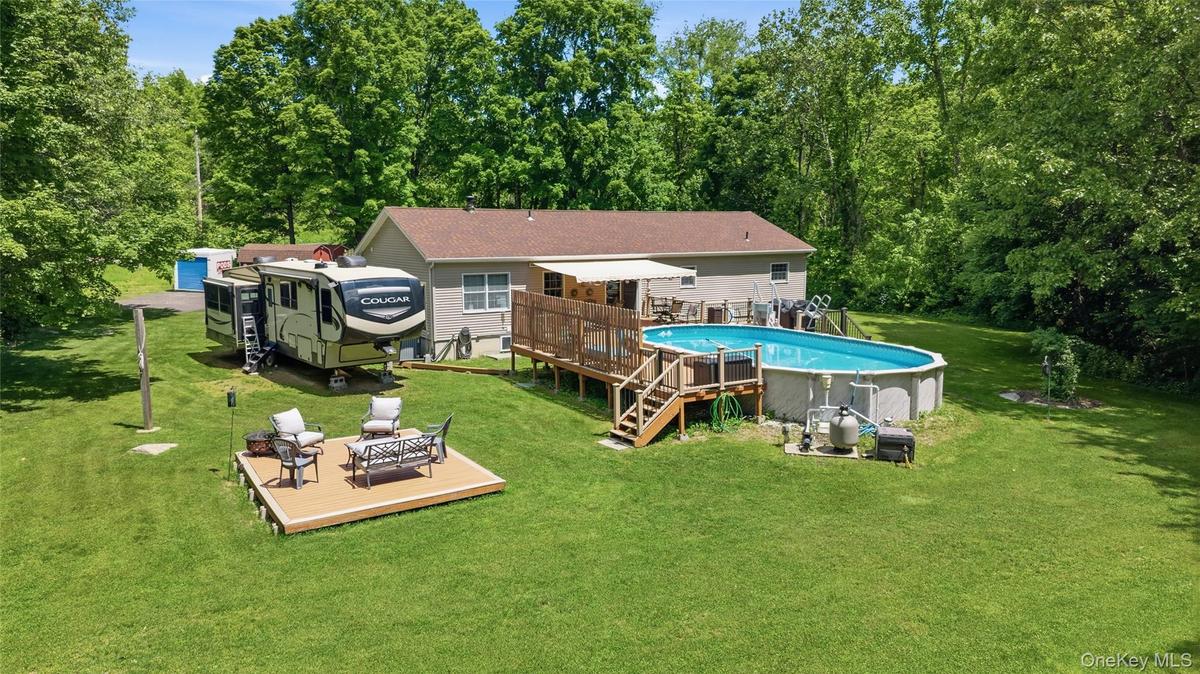 Expansive backyard featuring a large above-ground pool with a surrounding wood deck
