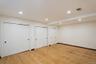 Room featuring wood-finish flooring, recessed lighting, crown molding, and multiple double-door closets with black hardware