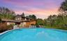 Back of house featuring an outdoor pool, a patio, and a yard