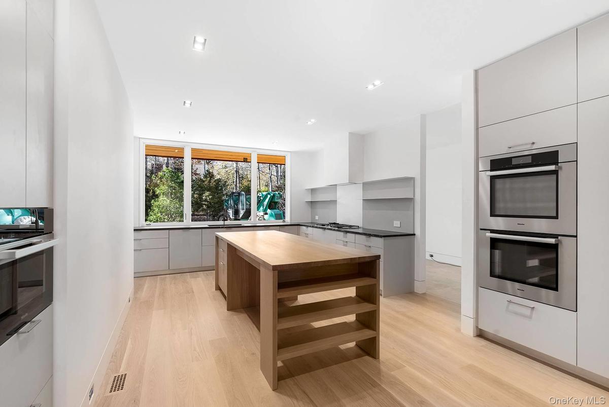 Kitchen featuring stainless steel appliances, modern cabinets, a center island, butcher block countertops, and recessed lighting