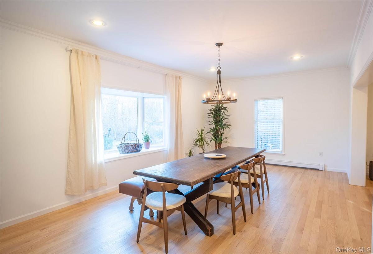 Dining space with ornamental molding, a chandelier, and light wood-style floors