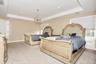 Bedroom featuring a tray ceiling, recessed lighting, light carpet, radiator, and a chandelier