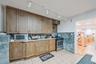 Kitchen featuring light countertops, stainless steel appliances, light tile patterned floors, track lighting, and brown cabinets