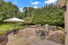 Expansive stone patio with a built-in outdoor kitchen, integrated fire pit, and stone retaining wall