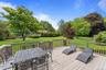 Spacious outdoor deck with wood-finish flooring and a wood railing overlooking an expansive manicured lawn