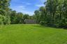 Expansive green lawn providing a substantial outdoor area, bordered by a dense tree line