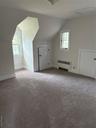 Additional living space featuring lofted ceiling, radiator heating unit, and light carpet