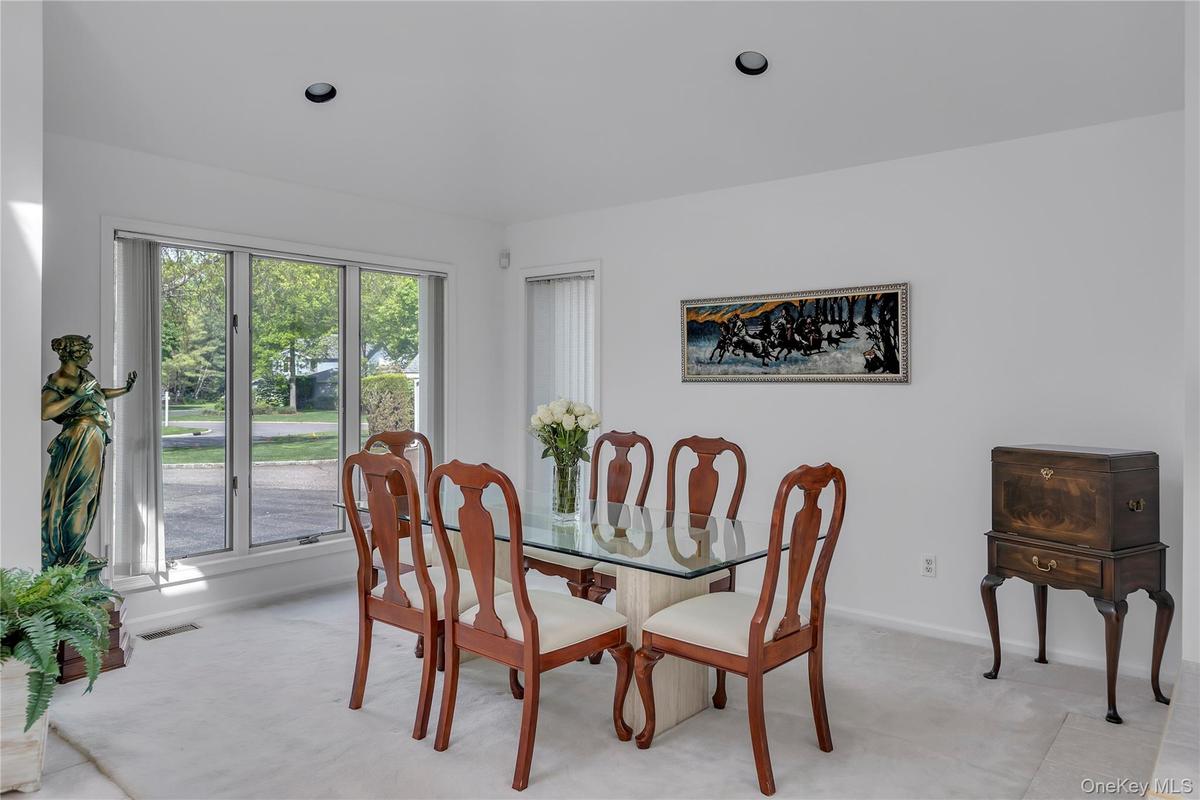 Bright dining area featuring a three-panel window, recessed ceiling lighting, and light-toned wall-to-wall carpeting
