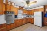 Kitchen featuring white appliances, light countertops, brown cabinetry, and ornamental molding