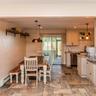 Kitchen and dining area featuring tile flooring, cream cabinetry, subway tile backsplash, and sliding glass door