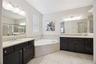 Primary bathroom features dual vanities and a garden tub