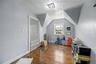 Sloped ceiling room featuring wood-finish flooring, a double window, and a flush-mount light fixture