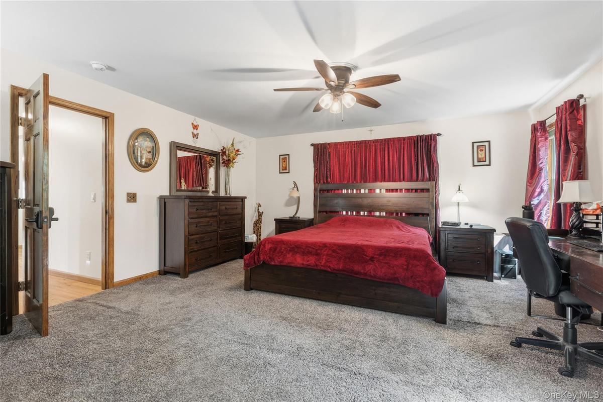 Spacious room featuring neutral carpeting, white walls, and a ceiling fan with integrated lighting