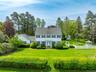 Colonial home featuring a chimney and view of wooded area
