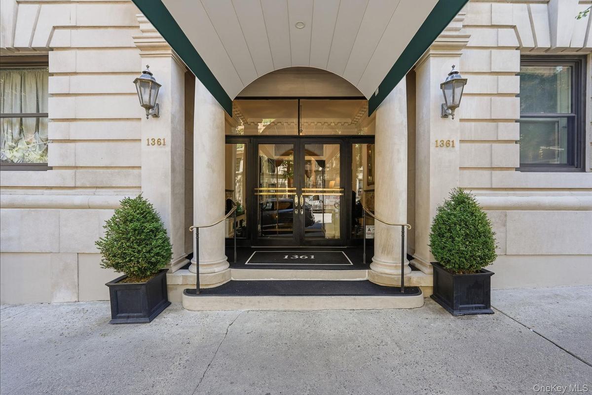 Building entrance featuring a stone facade, arched portico, and decorative outdoor sconces