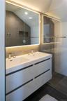 Full bathroom with lofted ceiling, tile walls, double vanity, walk in shower, and dark tile patterned flooring