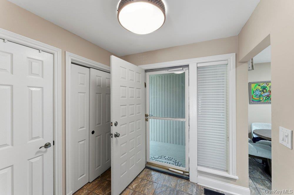 Entryway featuring tiled flooring, a flush-mount ceiling light, white paneled doors, and a front entry door with an adjacent window