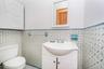 Bathroom featuring patterned tile wainscoting, a white pedestal sink with vanity, and a white framed mirror