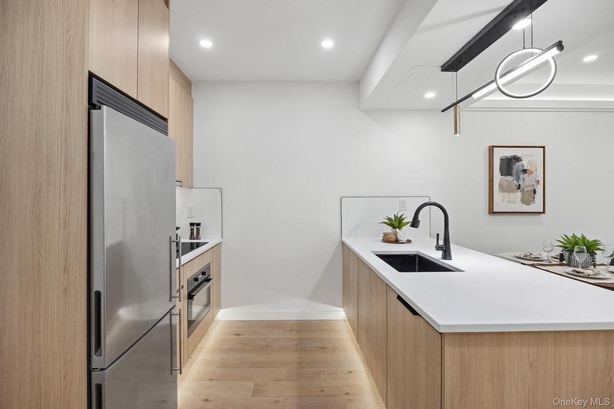 Kitchen featuring stainless steel appliances, modern cabinets, light brown cabinets, a sink, and recessed lighting