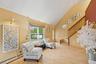 Living area with a baseboard radiator, high vaulted ceiling, light wood-type flooring, and stairway