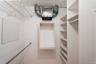White wall-mounted wire shelving system and built-in adjustable shelving units provide ample storage
