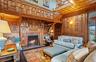 Living room featuring hardwood / wood-style floors, a high ceiling, a brick fireplace, wooden walls, and built in shelves