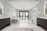 The oversized walk-in shower with floor-to-ceiling tile and dual showerheads has sliding glass door leading to an outdoor shower and private patio.