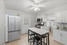 Kitchen featuring appliances with stainless steel finishes, white cabinets, decorative backsplash, light wood-style flooring, and a ceiling fan