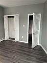 Unfurnished bedroom featuring baseboards, dark wood-type flooring, a baseboard heating unit, and a closet