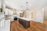 Kitchen featuring a kitchen island, stainless steel appliances, wall chimney exhaust hood, light hardwood / wood-style floors, and white cabinetry