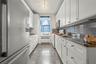 Kitchen featuring white appliances, granite floors, radiator, and white cabinetry