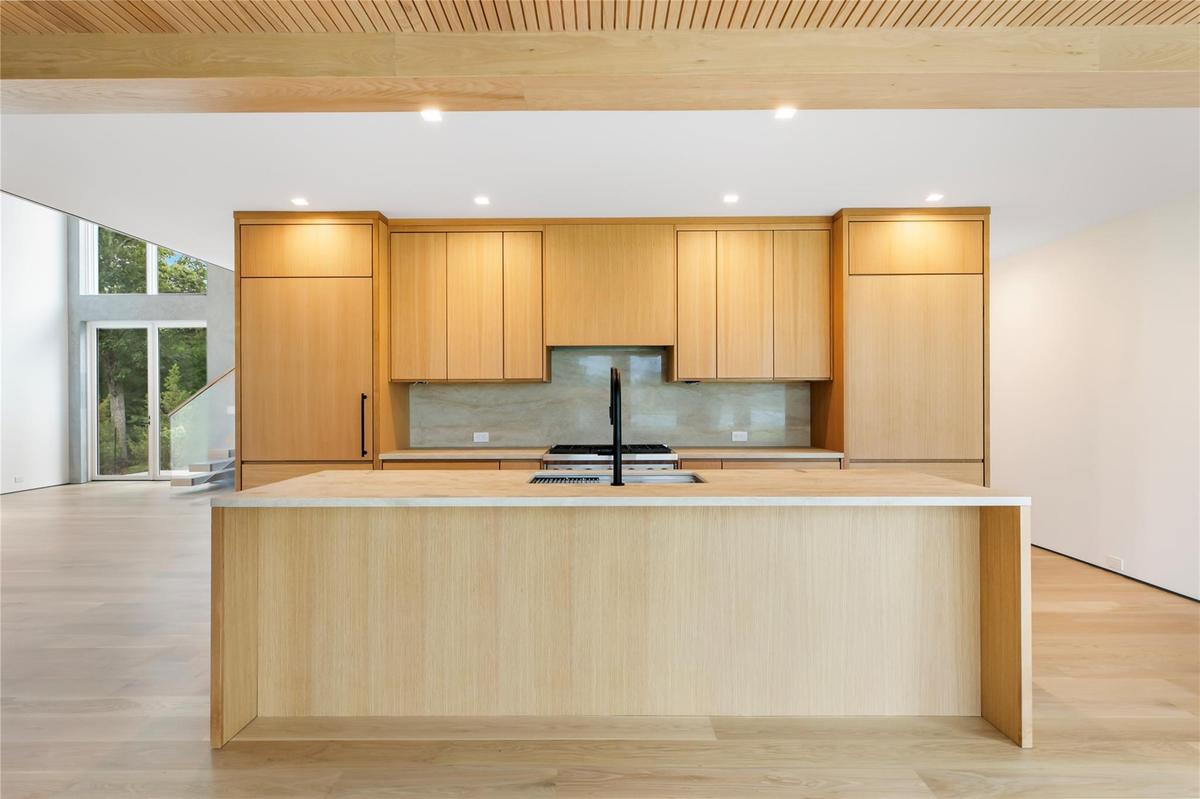 Kitchen featuring a large island, light countertops, light brown cabinets, recessed lighting, and expansive windows