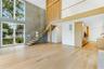 Unfurnished living room with a towering ceiling, light wood-type flooring, and stairway