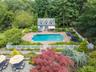 View of swimming pool featuring an exterior structure, an outbuilding, a forest view, a fenced backyard, and a patio