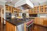 Kitchen featuring crown molding, tasteful backsplash, custom exhaust hood, built in appliances, and dark wood-type flooring